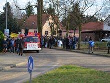Ein Feuerwehrwagen an einer Kreuzung ist auf dem Bild zu sehen. Vor dem Kühler ein großes Schild mit der Aufschrift "Kerkwitz sagt NEIN. Kein TagebauJänschwalde-Nord" Links und rechts von der Straße säumen viele Menschen den Weg. Es sind die Demonstranten bei diesem 8. Sternmarsch in der Braunkohle-Region.